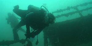 single scuba diver near sunken wreckage